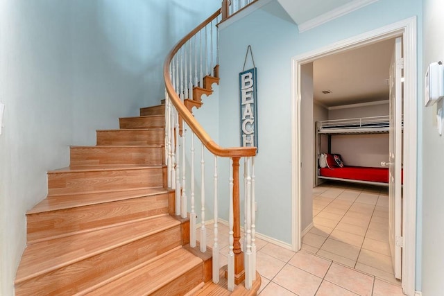 staircase featuring crown molding and tile patterned floors