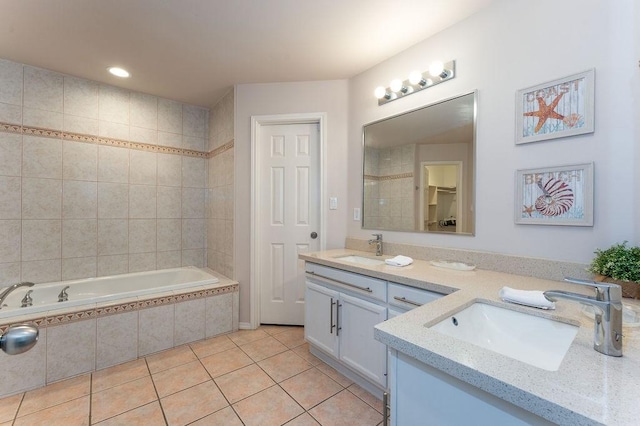 bathroom with tile patterned flooring, vanity, and tiled tub