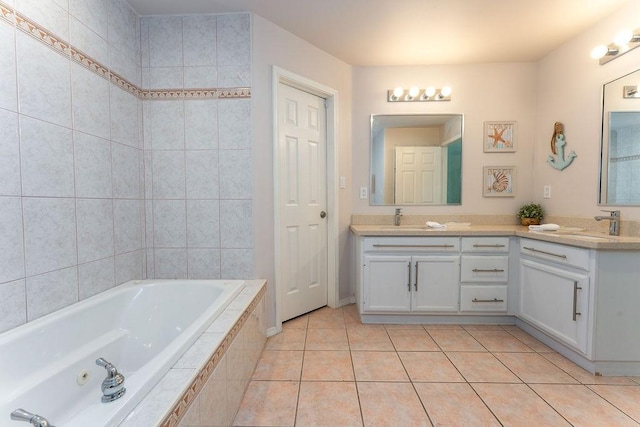 bathroom featuring tile patterned flooring, vanity, and tiled bath