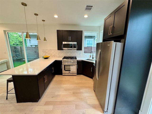 1708 Canterbury St Unit 2, Austin, TX 78702 - kitchen with appliances with stainless steel finishes, a sink, a peninsula, a breakfast bar, and light wood-style flooring