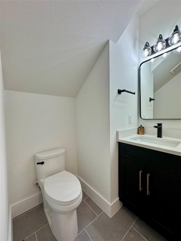 1708 Canterbury St Unit 2, Austin, TX 78702 - bathroom featuring toilet, vanity, lofted ceiling, baseboards, and a textured ceiling