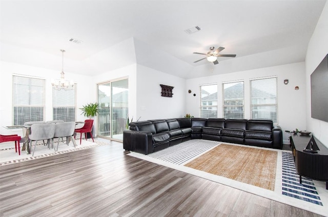 living room with ceiling fan with notable chandelier and hardwood / wood-style floors