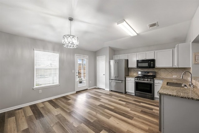 kitchen featuring sink, stone counters, stainless steel appliances, white cabinets, and decorative light fixtures