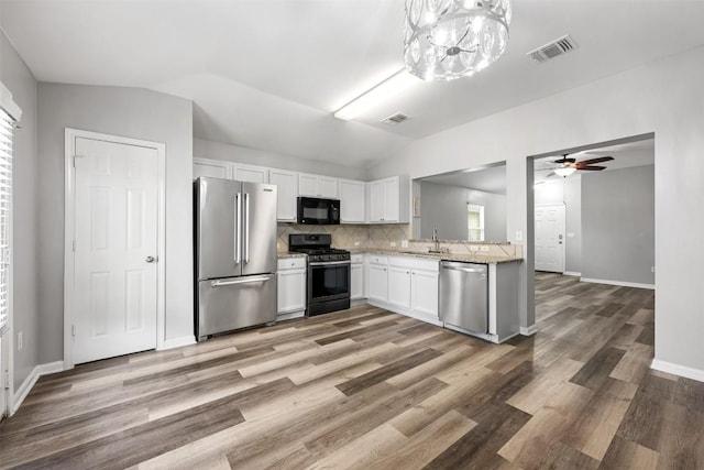 kitchen featuring vaulted ceiling, appliances with stainless steel finishes, tasteful backsplash, white cabinetry, and sink