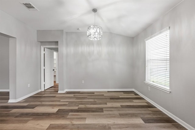 spare room featuring a chandelier and dark hardwood / wood-style flooring