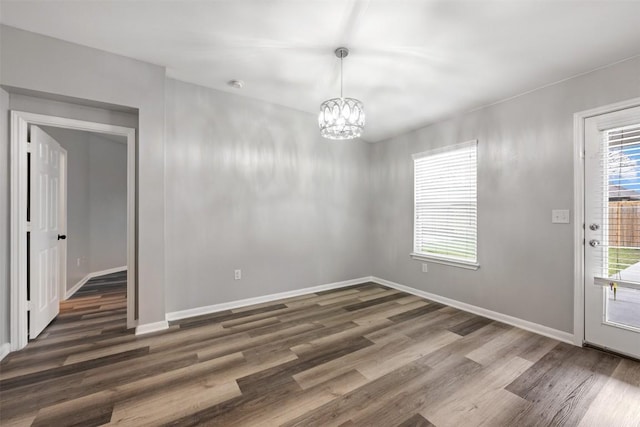 unfurnished dining area featuring dark hardwood / wood-style flooring and a notable chandelier