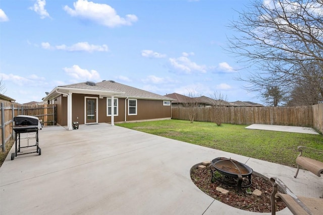 rear view of property featuring a patio area, a lawn, and an outdoor fire pit