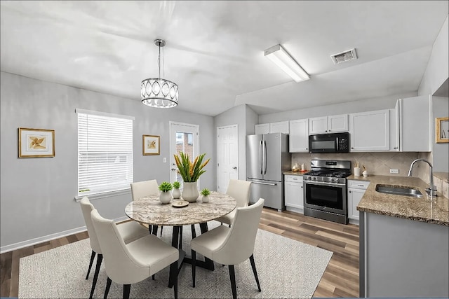 dining area with sink, dark wood-type flooring, and a chandelier