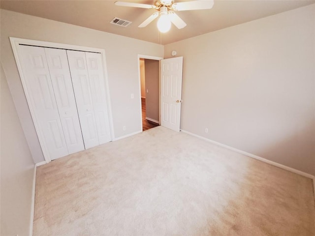 unfurnished bedroom featuring light carpet, a closet, and ceiling fan