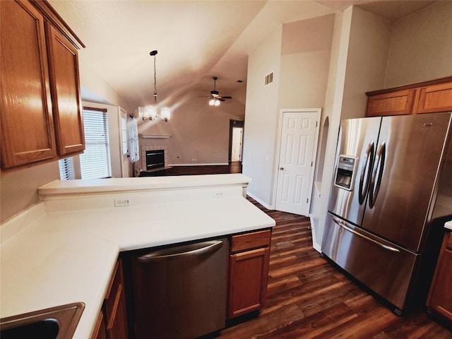 kitchen with dark wood-type flooring, an inviting chandelier, hanging light fixtures, appliances with stainless steel finishes, and kitchen peninsula