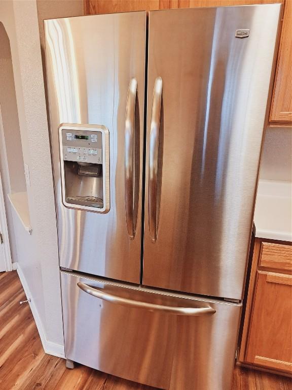 details featuring stainless steel fridge and light hardwood / wood-style flooring