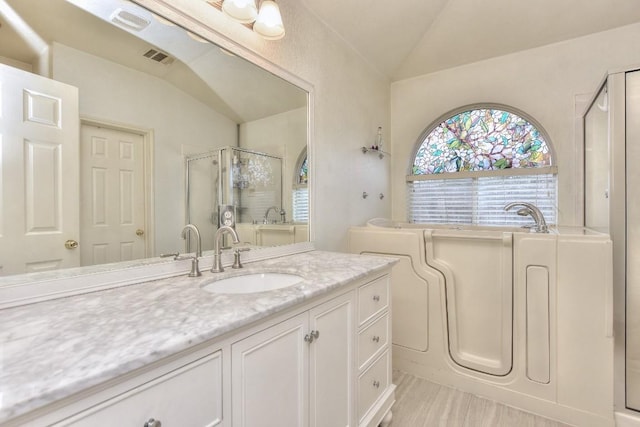 bathroom with lofted ceiling, a shower with shower door, and vanity