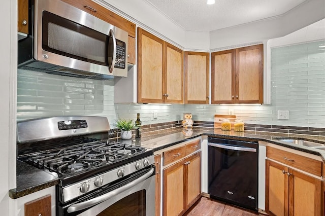 kitchen with tasteful backsplash, stainless steel appliances, a textured ceiling, and dark stone counters