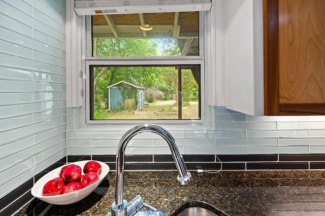 details featuring tasteful backsplash, sink, and dark stone counters