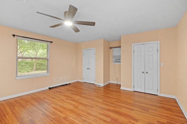 unfurnished bedroom featuring two closets, ceiling fan, and light hardwood / wood-style flooring