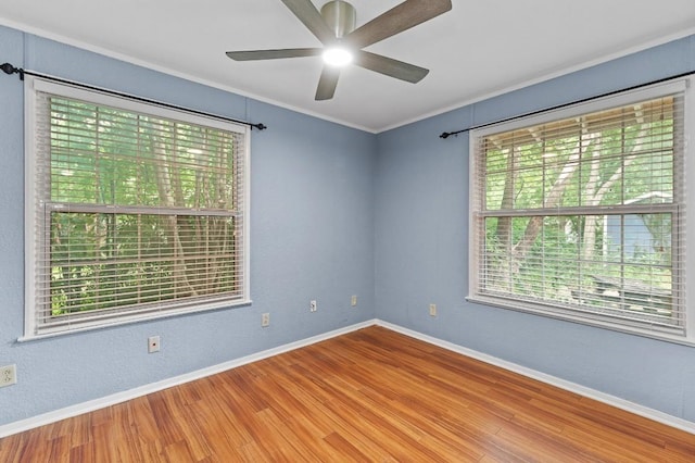 empty room featuring a wealth of natural light, ornamental molding, and wood-type flooring