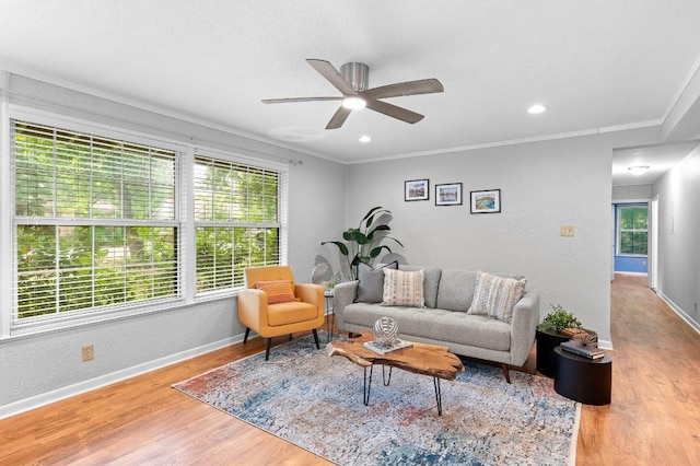 living room with ornamental molding, a textured ceiling, ceiling fan, and light wood-type flooring