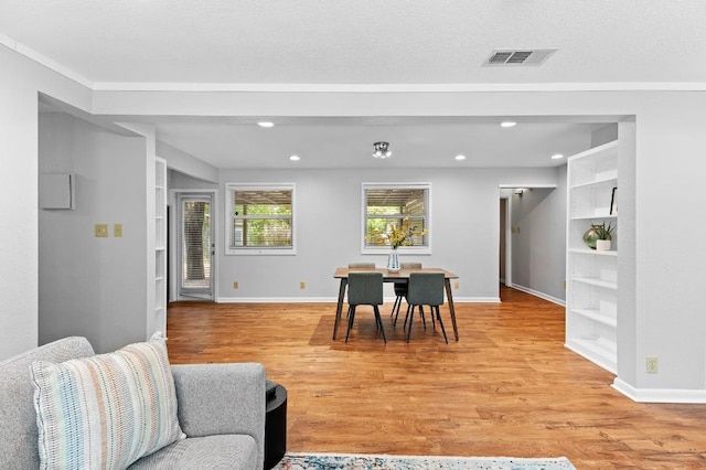 dining room featuring built in features, light hardwood / wood-style floors, and a textured ceiling