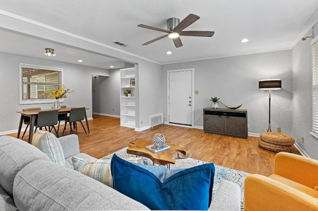 living room with hardwood / wood-style flooring, ornamental molding, and ceiling fan