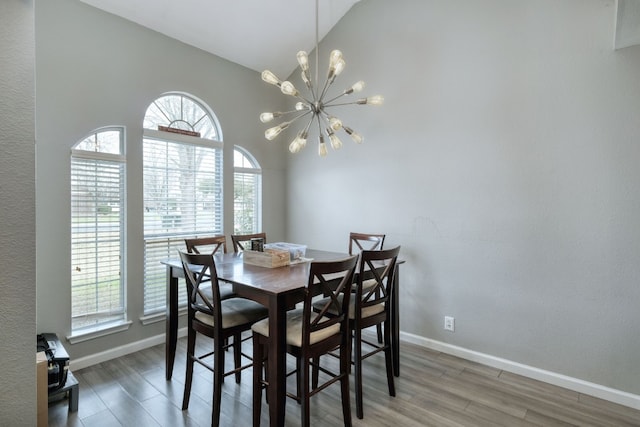 dining room with a chandelier, vaulted ceiling, and hardwood / wood-style flooring