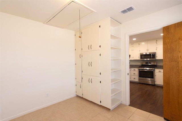 interior space with stainless steel appliances, white cabinetry, and light tile patterned floors