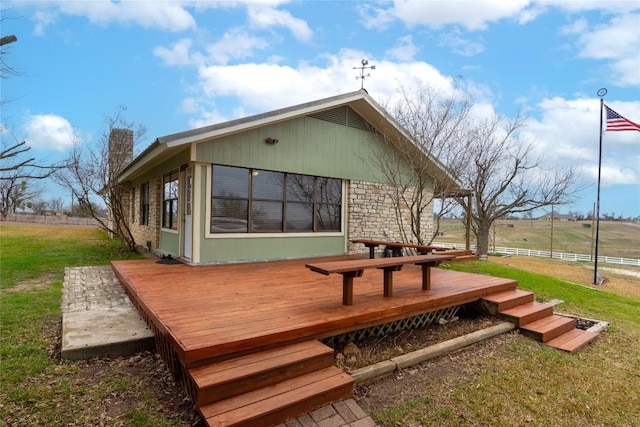 exterior space with a wooden deck, a rural view, and a lawn