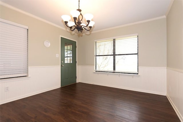 spare room featuring crown molding, dark wood-type flooring, and an inviting chandelier