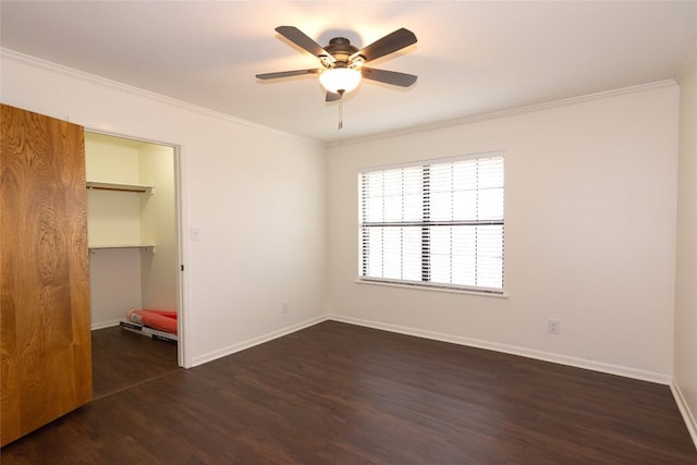 unfurnished bedroom with crown molding, a walk in closet, dark hardwood / wood-style floors, and a closet