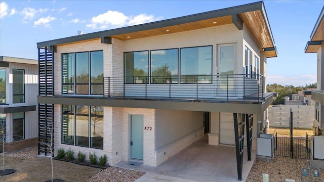 contemporary house featuring brick siding, stucco siding, stairs, and fence