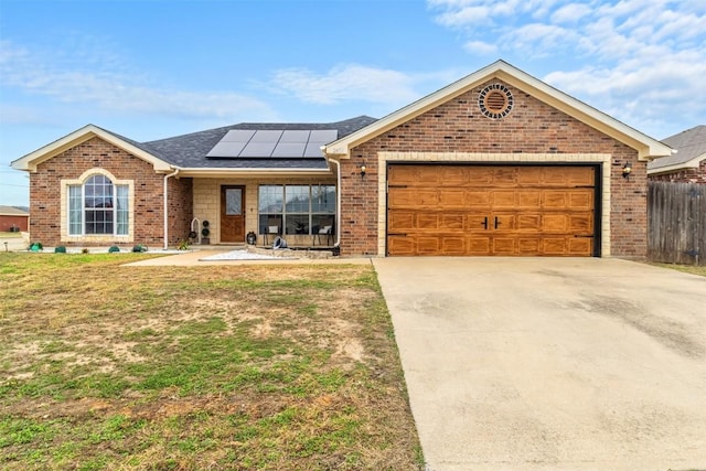 single story home with a garage, a front yard, and solar panels