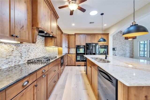 3701 Copper Ridge Ct, Austin, TX 78734 - kitchen with black appliances, a sink, light wood-type flooring, a spacious island, and decorative light fixtures