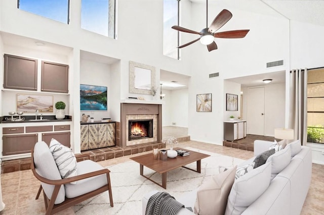 tiled living room featuring a tiled fireplace, sink, and ceiling fan