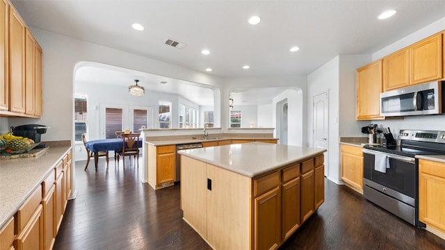 kitchen with dark wood-type flooring, a kitchen island, kitchen peninsula, and appliances with stainless steel finishes