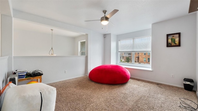 sitting room with ceiling fan and carpet