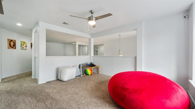 sitting room with ceiling fan and carpet