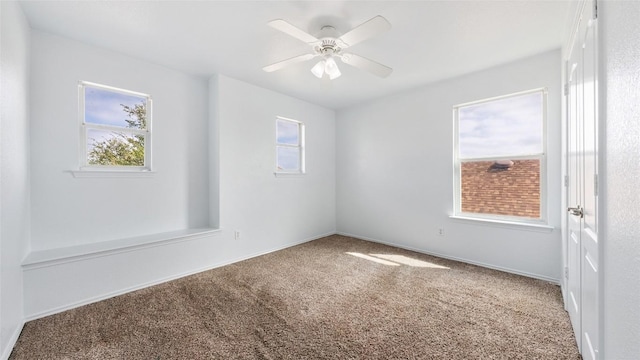 carpeted empty room featuring ceiling fan and plenty of natural light