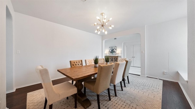 dining room with dark wood-type flooring and a chandelier