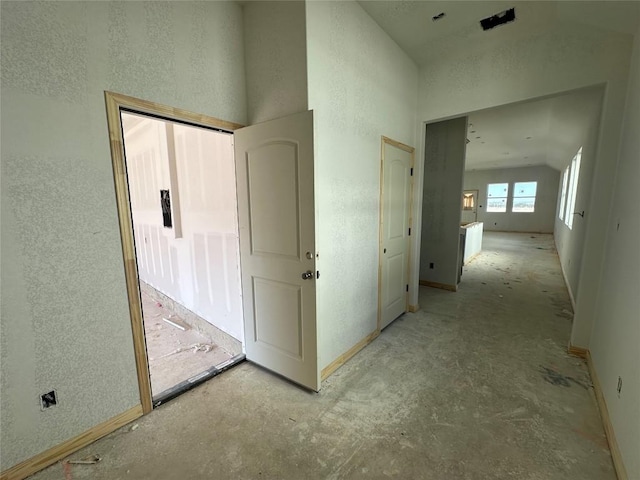 hall with lofted ceiling and a textured wall