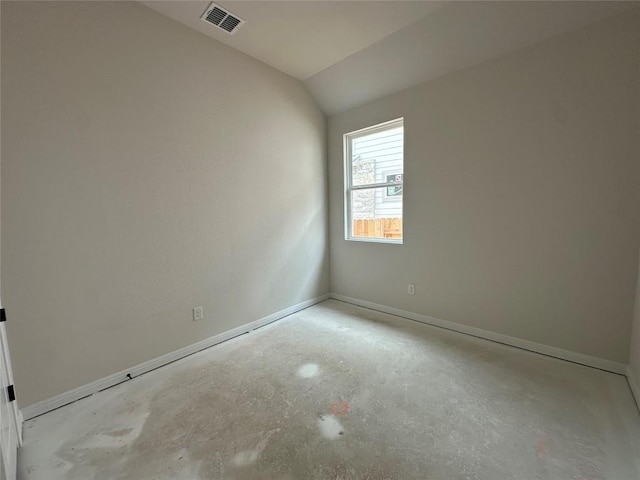 spare room with baseboards, concrete floors, visible vents, and vaulted ceiling