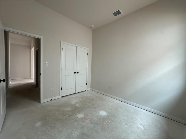 unfurnished bedroom with a closet, visible vents, concrete floors, and baseboards