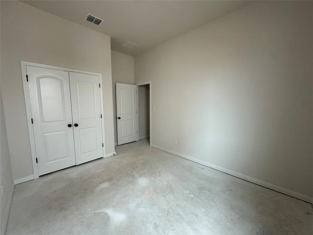 unfurnished bedroom featuring concrete floors, a closet, visible vents, and baseboards