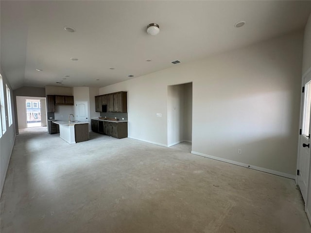 unfurnished living room with lofted ceiling, visible vents, a sink, concrete flooring, and baseboards