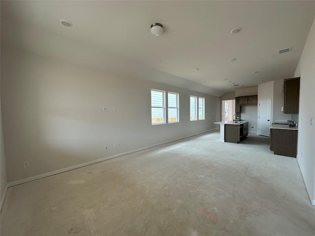 unfurnished living room featuring baseboards, a sink, visible vents, and unfinished concrete floors