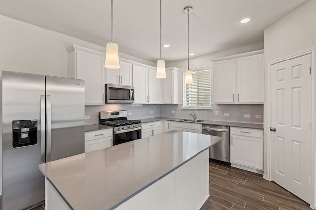 kitchen featuring appliances with stainless steel finishes, decorative light fixtures, white cabinetry, decorative backsplash, and a center island