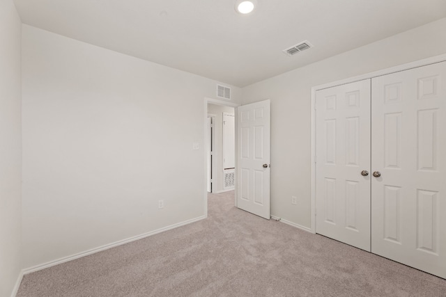 unfurnished bedroom with a closet and light carpet