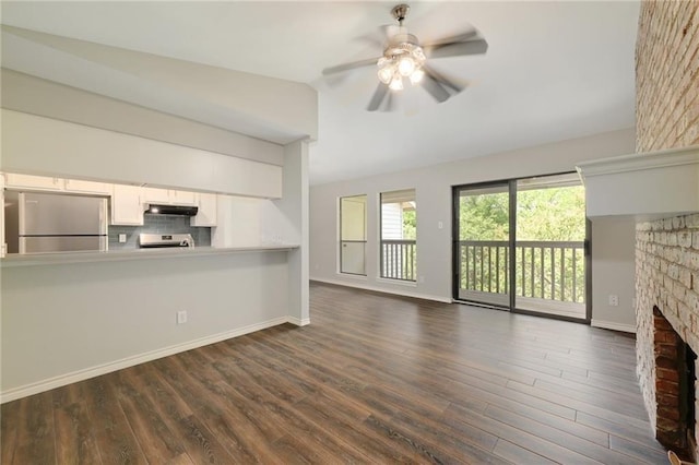 unfurnished living room with dark hardwood / wood-style floors, ceiling fan, a fireplace, and vaulted ceiling