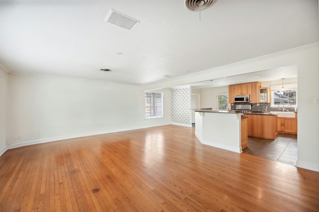 unfurnished living room featuring crown molding, a wealth of natural light, and light hardwood / wood-style flooring