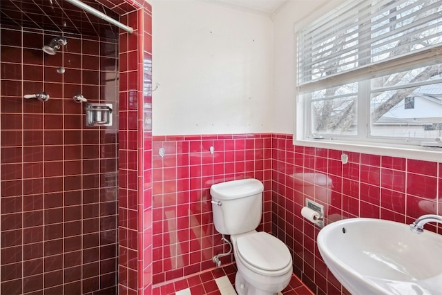 bathroom featuring toilet, sink, crown molding, tile walls, and a tile shower