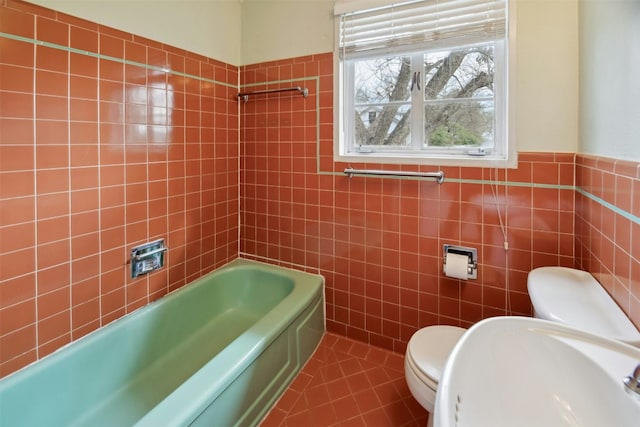 bathroom featuring a tub, sink, tile walls, tile patterned flooring, and toilet