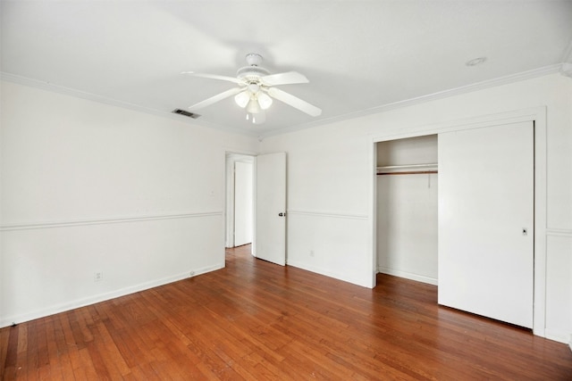 unfurnished bedroom featuring crown molding, ceiling fan, dark hardwood / wood-style flooring, and a closet